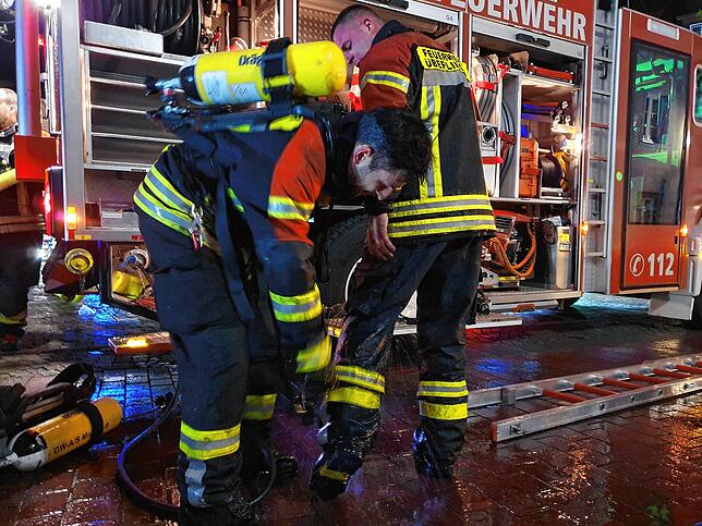 Nach ihrem Einsatz waschen sich die Atemschutzträger gegenseitig den gröbsten Schmutz von der Kleidung.