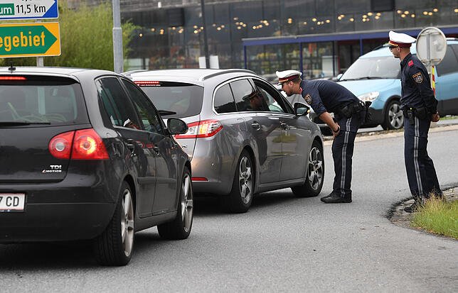Polizisten kontrollieren Fahrzeuge auf einer Bundestraße.