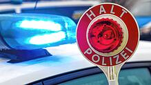 Ein Polizist hält eine Polizeikelle für eine Kontrolle auf einem Parkplatz an der Autobahn 72.