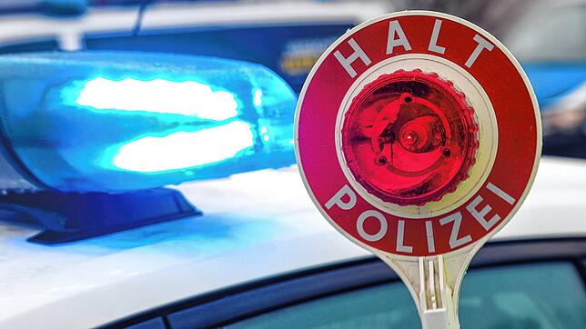 Ein Polizist hält eine Polizeikelle für eine Kontrolle auf einem Parkplatz an der Autobahn 72.