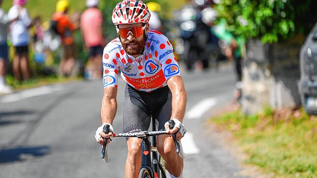 Simon Geschke im gepunkteten Trikot des besten Bergfahrers bei der Tour de France im Juli 2022. Auch der Helm passt farblich zum Hemd.