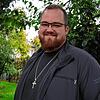 Jorin Jansen ist Pastor der Singener Friedenskirche, die 2022 abgebrannt und deren Baustelle im Hintergrund zu sehen ist. Er pflegt ein ...