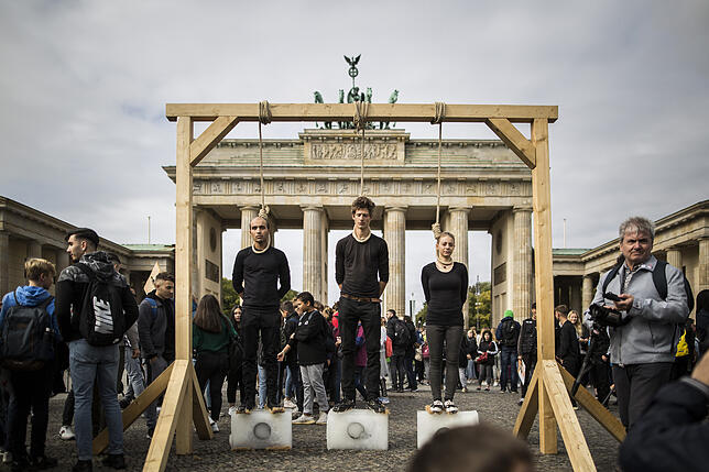 Im Rahmen einer Demonstration von „Fridays for Future“ stehen Aktivisten an einem Galgen auf Eisklötzen.