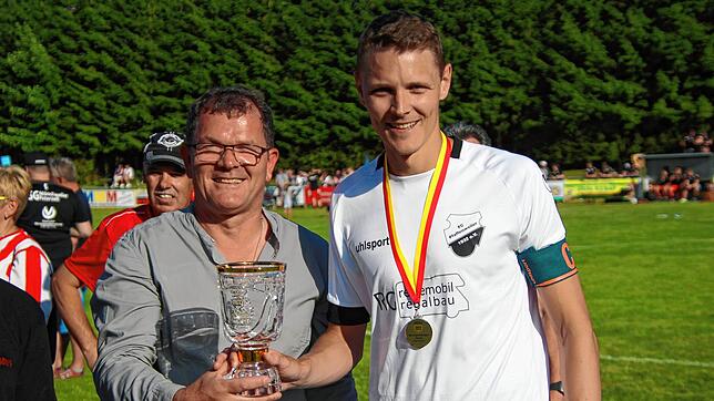 Bezirksvorsitzender Guido Seelig übergibt den Bezirkspokal den Pfaffenweilers Kapitän Adrian Scholemann.