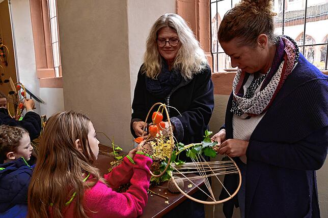 Liebevoll gestalten Theresa (Mitte) und Regina Engel mit Luisa ein herbstliches Blumengesteck.
