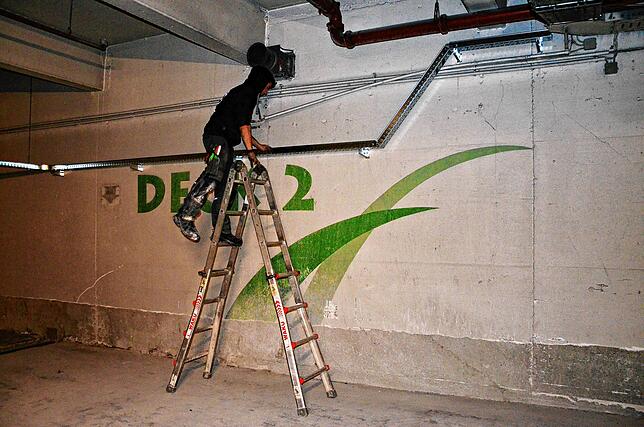 Ein Arbeiter ersetzt alte Leitungen, von denen es im ganzen Parkhaus mehr als 5 Kilometer gibt.