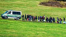 Flüchtlinge gehen am 27. Oktober 2015 in Bayern hinter einem Fahrzeug der Bundespolizei her.