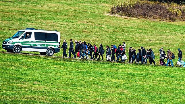 Flüchtlinge gehen am 27. Oktober 2015 in Bayern hinter einem Fahrzeug der Bundespolizei her.