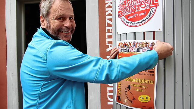 Die Vorbereitungen werden schon einmal getroffen: Narrizella-Präsident Martin Schäuble hängt ein Plakat für das Schlachtfest auf