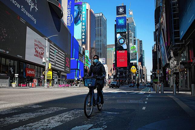 Eine Frau fährt mit Atemschutzmaske auf dem leeren Times Square Fahrrad.