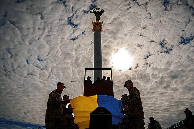 Ukrainische Soldaten legen die Nationalflagge auf den Sarg ihres gefallenen Kameraden während eines Trauer-Gottesdienstes auf dem ...