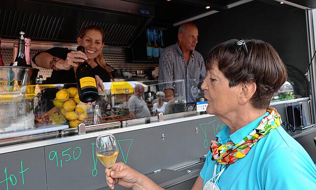 Barbara Späth bietet Beatrix Popp Champagner an.