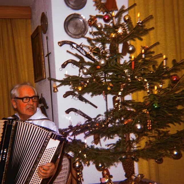 Gaby Hauptmanns Vater mit Akkordeon vor dem Weihnachtsbaum.