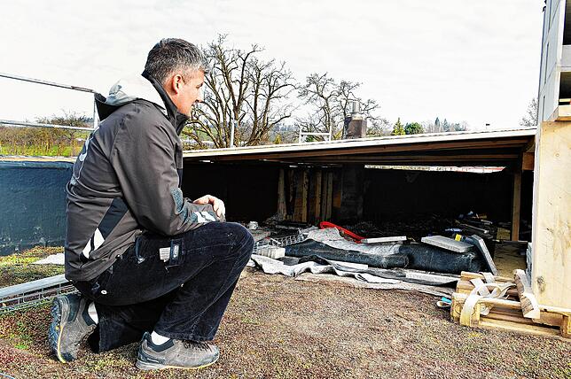 Sebastian Schmäh sitzt vor der Brandstelle auf dem Dach seiner Zimmerei. Die betroffene Stelle ist ihm zufolge etwa 15 Quadratmeter ...