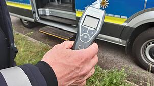 Ein Polizist hält einen Alcomaten in der Hand. (Symbolbild) In Waldshut hat eine Streife einen betrunkenen Autofahrer aus dem Verkehr ...