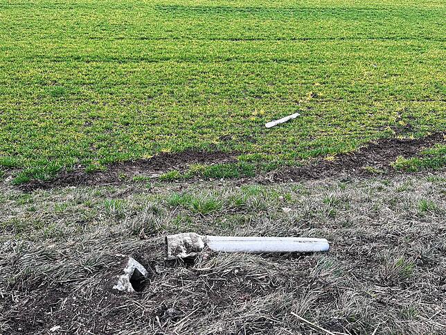 Ein demolierter Leitpfosten liegt am Straßenrand.