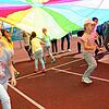 Glückliche Kinder in der Ferienbetreuung der Schulsozialarbeit: Unter dem neuen Fallschirm lässt es sich toll spielen.