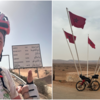 Links: Tankred Kauf vor einem Schild in der Sahara. Rechts: Das Fahrrad von Kauf angelehnt an marokkanischen Flaggen in der Wüste.