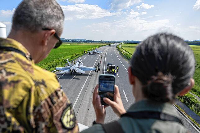 Menschen fotografieren zwei Kampfflugzeuge vom Typ F/A-18.