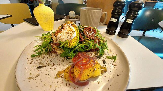 Ein reichhaltiges spätes Frühstück: Vollkorn-Toast mit Avocado-Basilikum-Creme, getrockneten Tomaten, einer halben Avocado, Körnern, ...