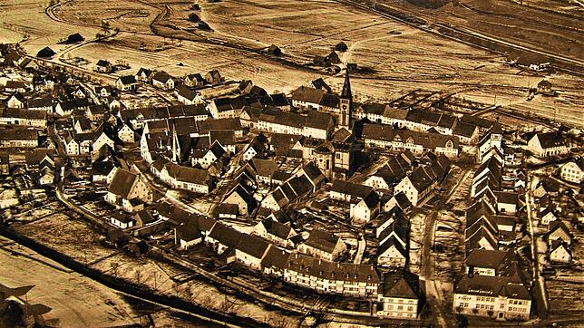 Eine alte Luftaufnahme zeigt den Blick über die Kernstadt Richtung Bregenberg mit Stadttor, Schulhaus und Stadtkirche.