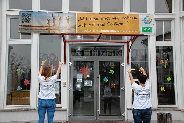 Die Glücksbeauftragten Teresa Scheu (links) und Tina Kiene mit den Plakaten zur Aktion „Das Glück kommt nach...“.
