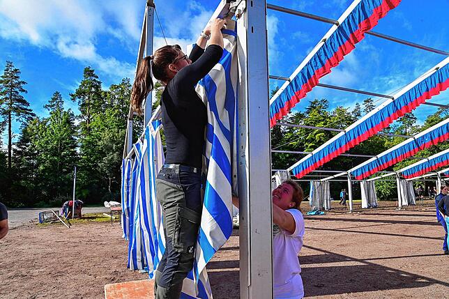 Sandra Schreiber (rechts) und Claudia Muckle hängen die weiß-blau-gestreifen Planen des Festzeltes ein.