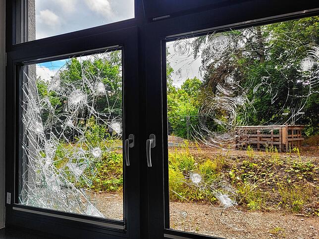 Blick auf dem Rektorat durch das zerstörte Fenster. Dahinter befinden sich der Innenhof der Schule, hinter den Bauzäunen halten sich ...