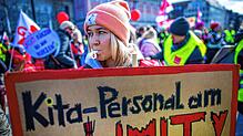 Eine Erzieherin steht mit einem Schild mit dem Schriftzug „Kita-Personal am Limit“ bei einer Kundgebung der Gewerkschaft Verdi in ...