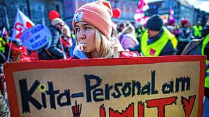 Eine Erzieherin steht mit einem Schild mit dem Schriftzug „Kita-Personal am Limit“ bei einer Kundgebung der Gewerkschaft Verdi in ...