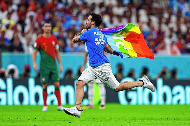 Ein Flitzer mit der Regenbogenflagge und politischen Botschaften zur Ukraine und Iran auf dem T-Shirt läuft beim Gruppenspiel Portugal ...