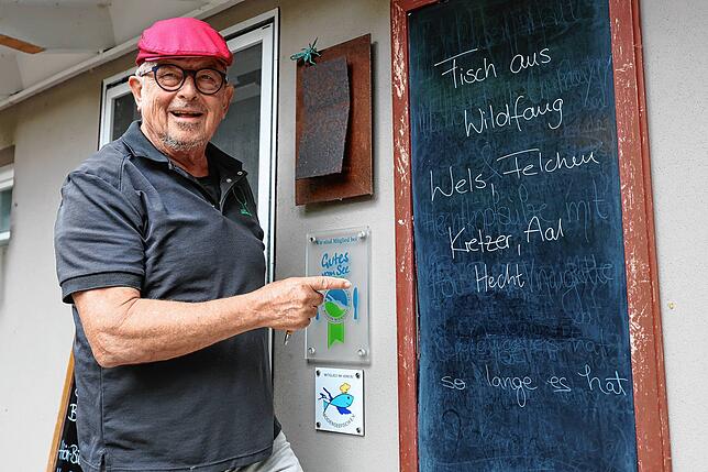 Hubert Neidhart an einer Tafel vor seinem Restaurant Grüner Baum in Moos. Diese zeigt: Hier gibt es Fisch