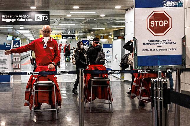 Mitarbeiter des Fiumicino-Flughafens bei Rom gibt Anweiseungen an gerade angekommene Reisende.