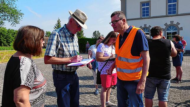 Auch Gisela und Egon Kernler (von links) tragen sich in die Unterschriftenliste ein. In Warnweste Walter Faigle von der Bürgerinitiative.