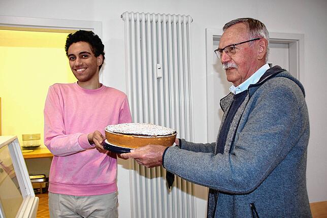 Praktikant und Vesperkirchenhelfer Etienne Mestre (links) nimmt einen Kuchen von Eberhard Krause entgegen.