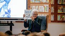 Ministerpräsident Winfried Kretschmann hält in der Grundschule Schlaitdorf das Buch in die Höhe, aus dem er vorlesen will.