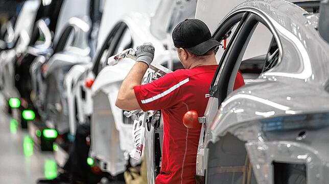 Ein Mitarbeiter der Porsche AG montiert im Stammwerk in Zuffenhausen einen vollelektrischen Porsche Taycan.