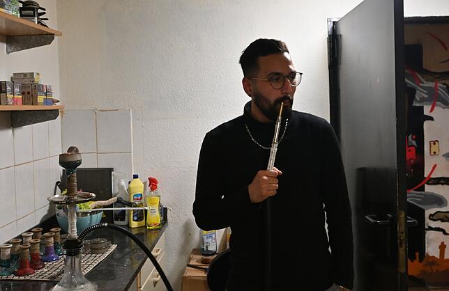 Selim Özdes raucht eine Shisha an. Wenn gewünscht, bekommt der Gast die Wasserpfeife vorbereitet, dass er das nicht selbst machen muss.