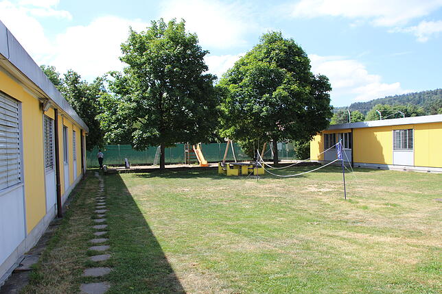 Im Innenhof des Asylzentrums gibt es einen Spielplatz, im Hintergrund verläuft ein Zaun – ohne Stacheldraht.