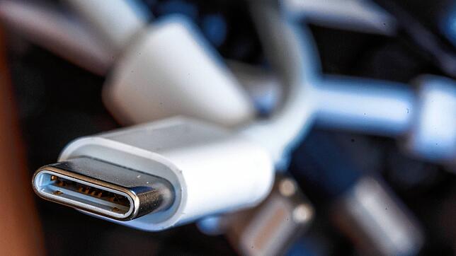 Ein Ladekabel mit USB-C-Stecker liegt neben einem Bündel unterschiedlicher Anschlusskabel. Ab 2024 soll es in der EU einheitliche ...