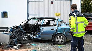 Ein Polizist steht an der Unfallstelle. Eine 49-Jährige gerät mit ihrem Auto in einer Kurve ins Schleudern und prallt gegen eine Wand. ...