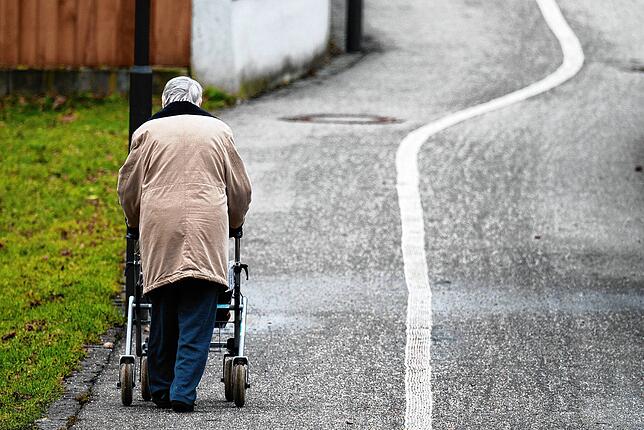 Eine ältere Frau geht mit einem Rollator auf einem Weg entlang. Besonders Frauen haben eine kleine Rente. Private Vorsorge wird immer ...
