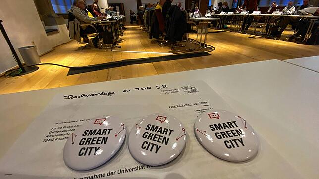 Werbung für das Programm mit allen Mitteln: Auf einem Tisch des Konstanzer Ratssaals liegen Anstecker, die für Smart Green City werben, ...