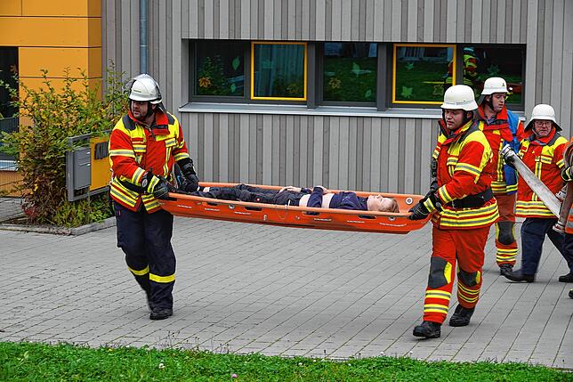 Dem Rauch entkommen: Zwei Feuerwehrmänner tragen einen Verletzten aus dem Kindergarten.