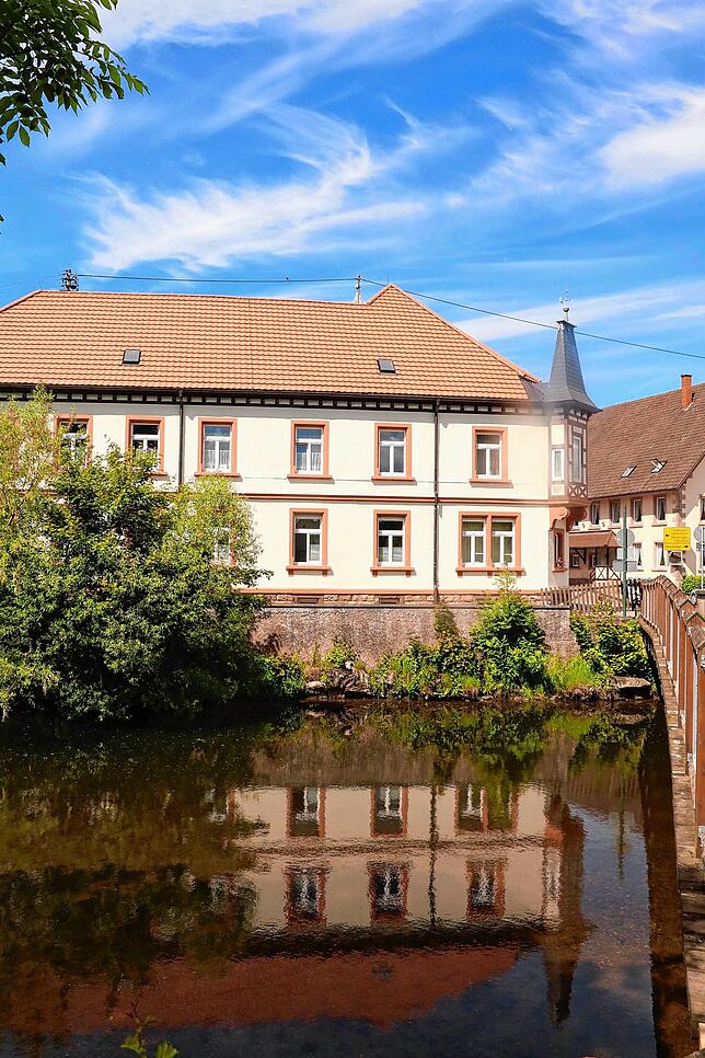Neben der Brücke spiegelt sich das Rathaus im Wasser.
