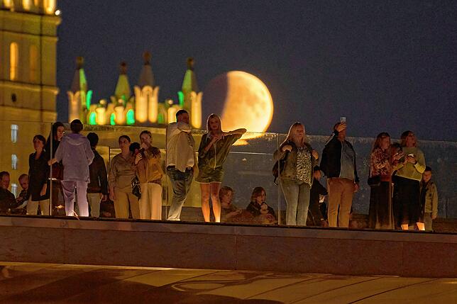 Die Mondfinsternis ist in Moskau außerdem über der Schwimmenden Brücke zu sehen, während Menschen den Herbstabend im Zaryadye Park genießen.