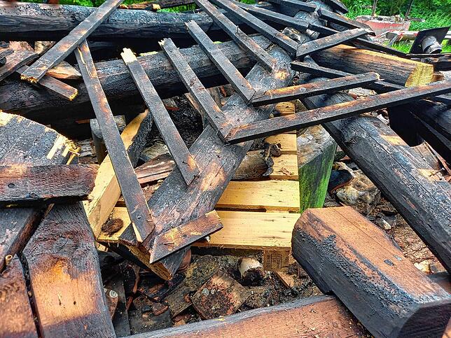 Die gehört da nicht hin: Im Brandschutt liegt auch eine Holzpalette. Die verkohlten Überreste der Grillstelle müssen als Sondermüll ...