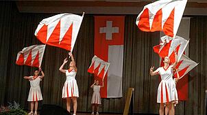 Große Kunstfertigkeit: Anmutig schwingt und wirft beim Heimatabend die Zunftgruppe der Fahnenschwingerinnen die rot-weißen Flaggen.