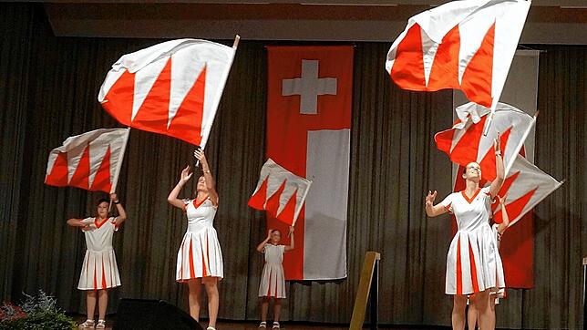 Große Kunstfertigkeit: Anmutig schwingt und wirft beim Heimatabend die Zunftgruppe der Fahnenschwingerinnen die rot-weißen Flaggen.