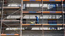 Ein Arbeiter geht auf der Baustelle eines Wohnhauses in Berlin mit einer Schubkarre über das Baugerüst. In Deutschland fehlen ...